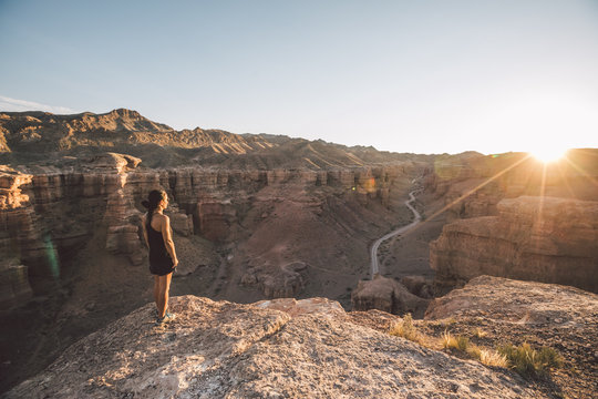 sporty woman enjoying sunset on top of charyn canyon