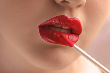 The girl puts red lipstick on sexy tender lips. Gentle makeup. Beauty high fashion trendy red lip color, seductive mouth.