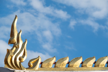 gold gables sculptured as mythical serpent-like being are seen decorating roof top of Wat Phra Si Rattana Mahathat temple, Phitsanulok provice, Thailand. Blue sky background