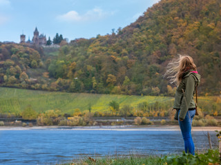 young girl next to a river and looking at a castle on the mountain