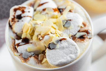 cup of coffee with marshmallow and topping with nuts