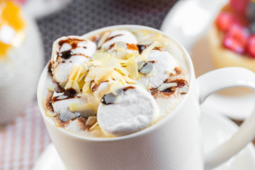 cup of coffee with marshmallow and topping with nuts