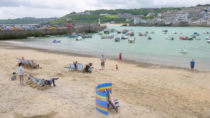 People sitting in deckchairs enjoying the summer on St Ives beach, Cornwall.