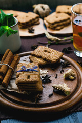 Speculaas Christmas cookies on a wooden board sprinkled with powdered sugar with mint leaves and oriental spices. Tea with mint, lemon and oriental spices