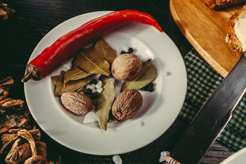 Dried porcini mushrooms with spices and chili peppers on a white dish. Variety of vegetables
