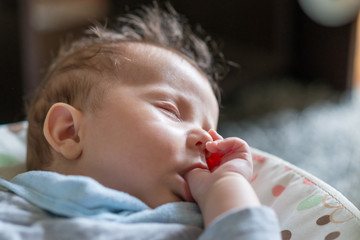 Sleeping baby in swing automatic electrical chair and sucking left thumb