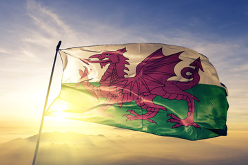 Wales welsh flag textile cloth fabric waving on the top sunrise mist fog