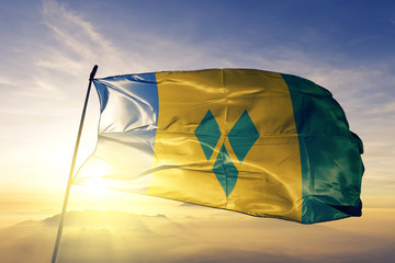 Saint Vincent and the Grenadines flag textile cloth fabric waving on the top sunrise mist fog