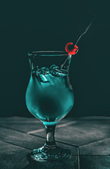 blue cocktail glass with ice and cherry