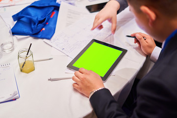 Blurred background, people sitting at the white round table - in the middle of the table is a tablet