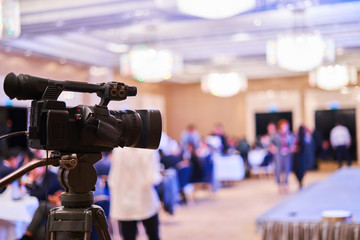 video camera stands on a tripod - video of the conference, blurred background