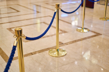 golden fence with a blue rope - marble floor, background
