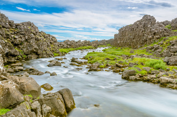 Fototapeta na wymiar A smooth river inside the middle Atlantic ridge at thingvellir. A well-known location in the golden circle in Iceland. The only place on earth where the dosal rises above the earth