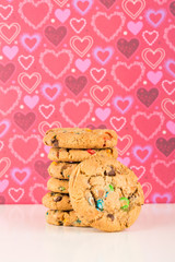 chocolate chip cookies on white table and pink valentine's day hearts background, stacked cookies
