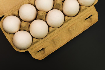 pack of chicken eggs on black background