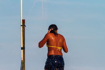 African-American girl takes a shower on the beach