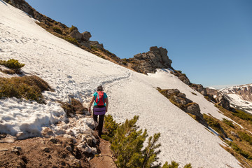 Tourist in a T-shirt climbing a snowy path to the mountains