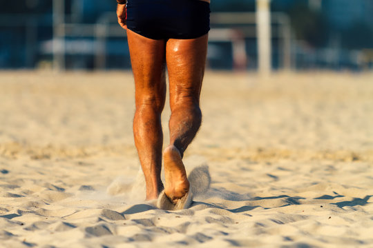 Legs Of Senior Man With Swimsuit Walking On The Beach