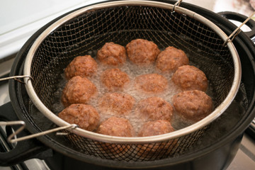frying meatballs in fryer filled with oil