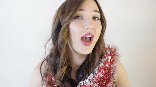 Santa girl sings Christmas songs. Sexy red lips and curly hair. Live video, HD