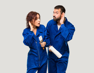 Painters listening to something by putting hand on the ear on isolated grey background