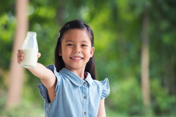 Cute little asia girl is drinking milk in bottle