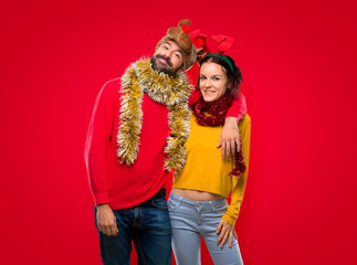 Happy couple dressed up for the christmas holidays on isolated red background