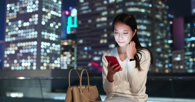 Woman work on mobile phone in city at night