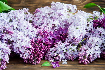 Purple flowers of lilac with leaves on a wooden background