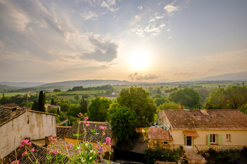 Fototapeta na wymiar Vue panoramique sur la vallée de Luberon, Provence, France depuis le village d'Ansouis. Fleurs de valériane rouge au premier plan. Coucher de soleil.