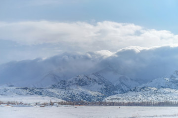 Winter mountains. Snow covered mountains. Winter landscape. Sunny day in the winter in the foothills. Clouds over snowy mountains.