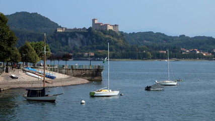 Fototapeta na wymiar lago maggiore con barche e rocca di angera in italia, maggiore lake with boats and angera fortress