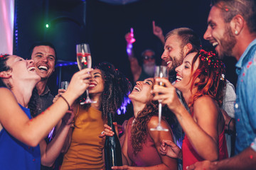 Group of friends dancing and drinking champagne at nightclub party - Happy young people having fun celebrating together in disco club - Entertainment, nightlife and youth lifestyle