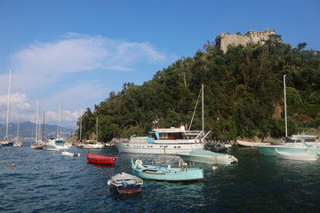 Fototapeta na wymiar PORTOFINO, ITALY - view of the medieval Castello Brown, built for harbor defence in 15th century, towering above the Portofino bay and the boats moored