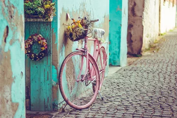 Poster Im Rahmen Rosa Vintage Fahrrad mit Korb voller Blumen neben einem alten cyanfarbenen Gebäude in Spanien © madrolly