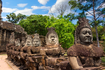 Row stone carved statues Asuras holding a body naga on right side bridge of South gate of Angkor Thom near Bayon temple in Siem Reap, Cambodia. Main entrance to the city. Popular tourist attraction