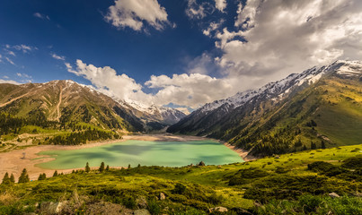 The mountain lake and mountain glaciers are lit by the rays of the sun.