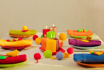 Multicolored plates and linen napkins with knitted decor. Table setting for the autumn or winter cold season - Thanksgiving, Halloween, Christmas and New Year.