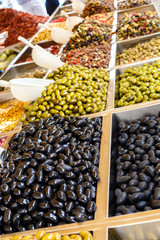Assortment of different olives for sale on the market window.