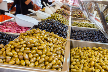 Assortment of different olives for sale on the market window.