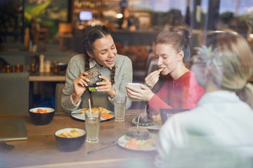 Cute girls making funny selfie by lunch while spending time in fast food cafe