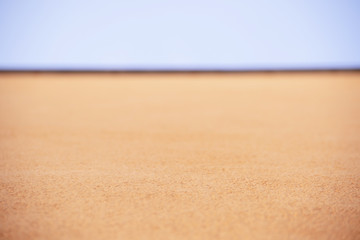 Horizontal texture of orange small stones and blue sky top view