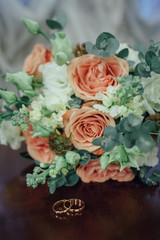 Bridal bouquet and two gold rings lie on a vintage table