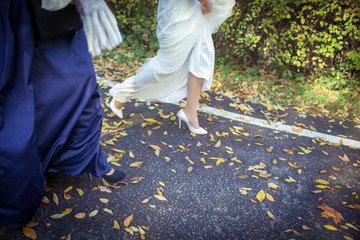 Legs of the bride and her bridesmaids on the path with autumn leaves