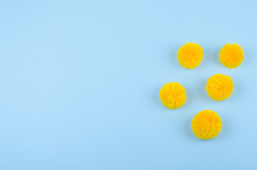 Yellow pom-pom on blue background with copy space 