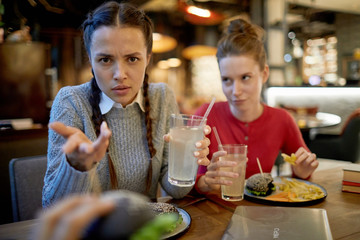 Rude girl in casualwear looking at you with aggressive expression while having lunch with friends