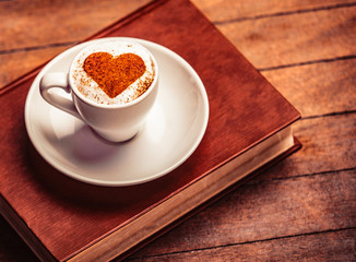 White cup of coffee and book on wooden table
