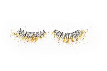 False eyelashes with gold sparkles on a white background.