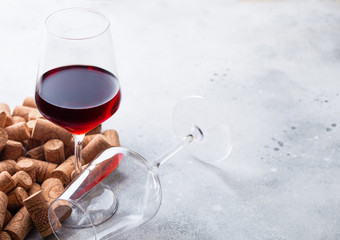 Elegant glass of red wine with corks on stone kitchen table background.