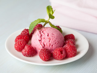 A raspberry ice cream with berries and mint leaves on a light background
